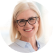 A smiling woman with glasses and light blonde hair, wearing a blue shirt, in a circular frame.
